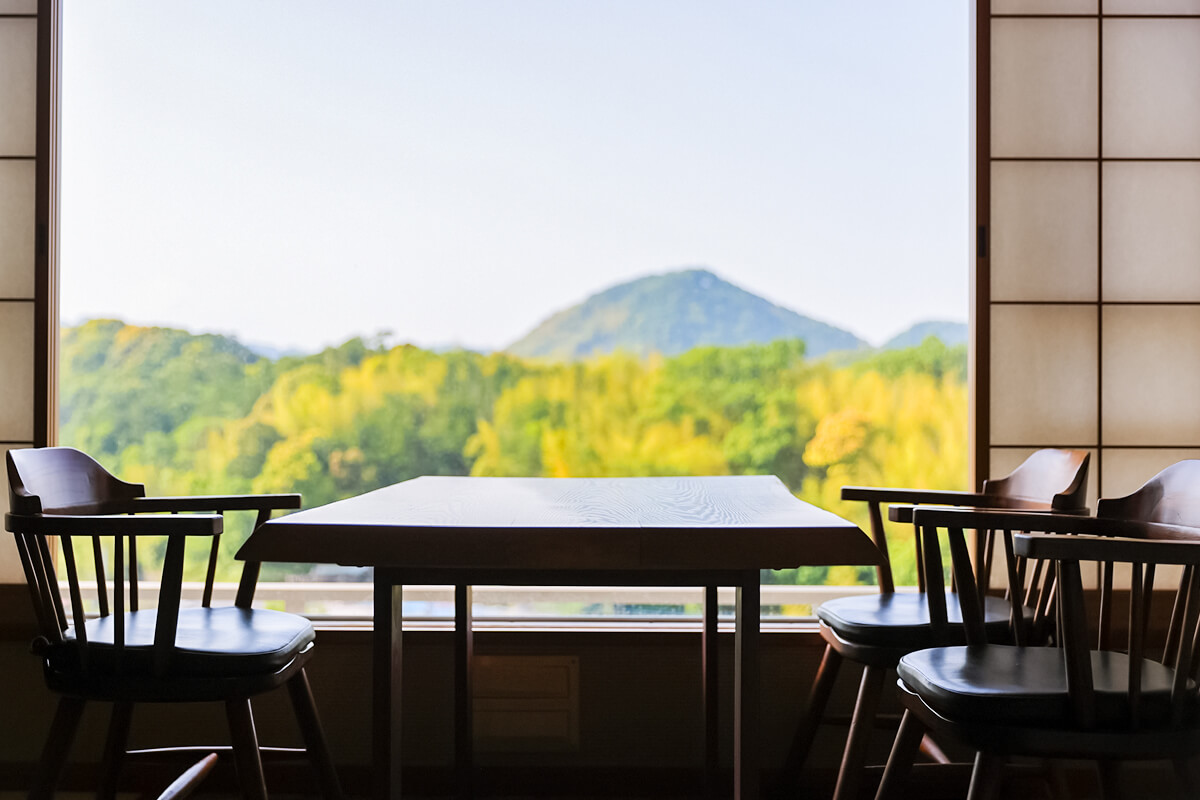 広緑のテーブルと椅子、窓から見える緑の山々