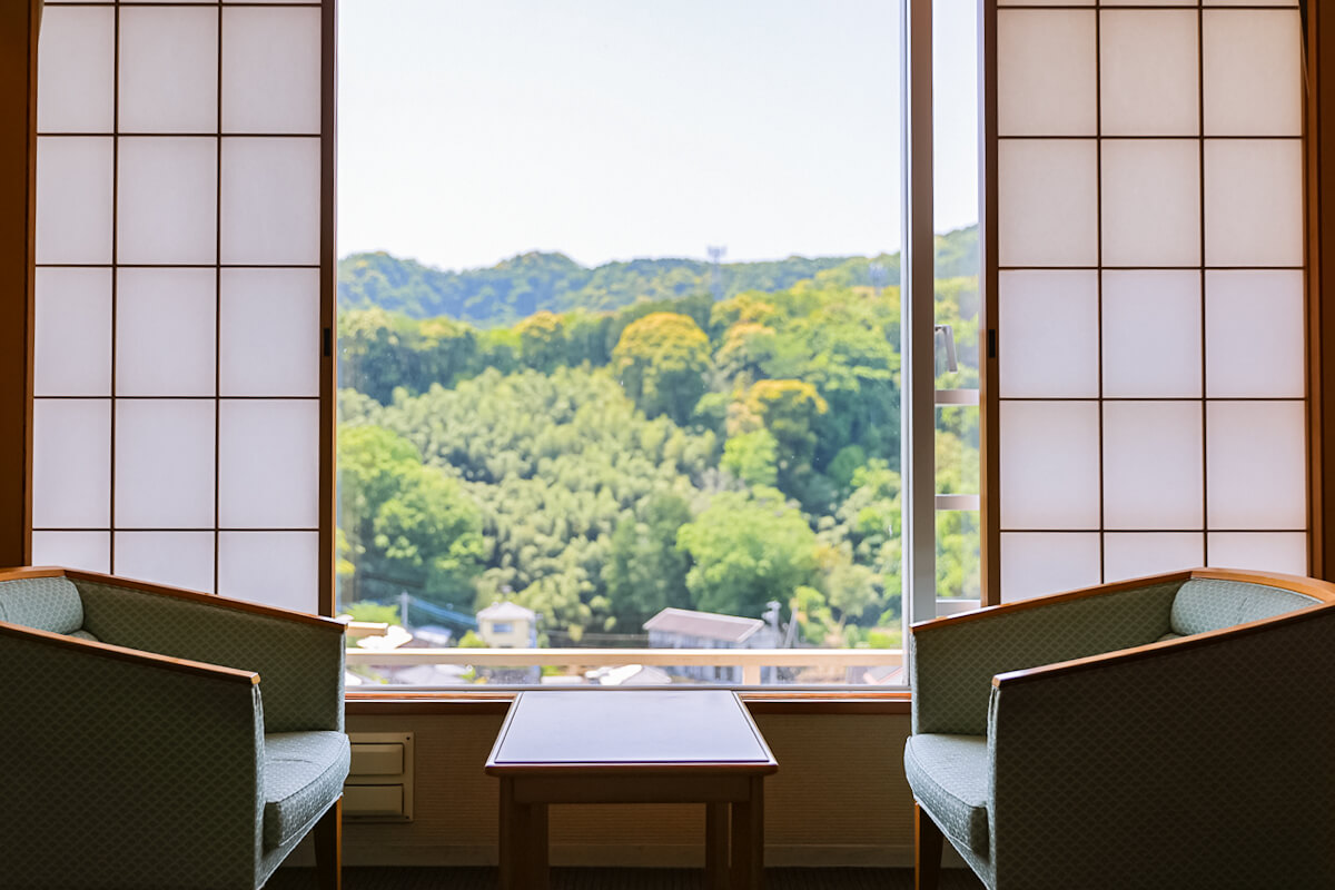 広緑のテーブルと椅子、窓から見える緑の山々